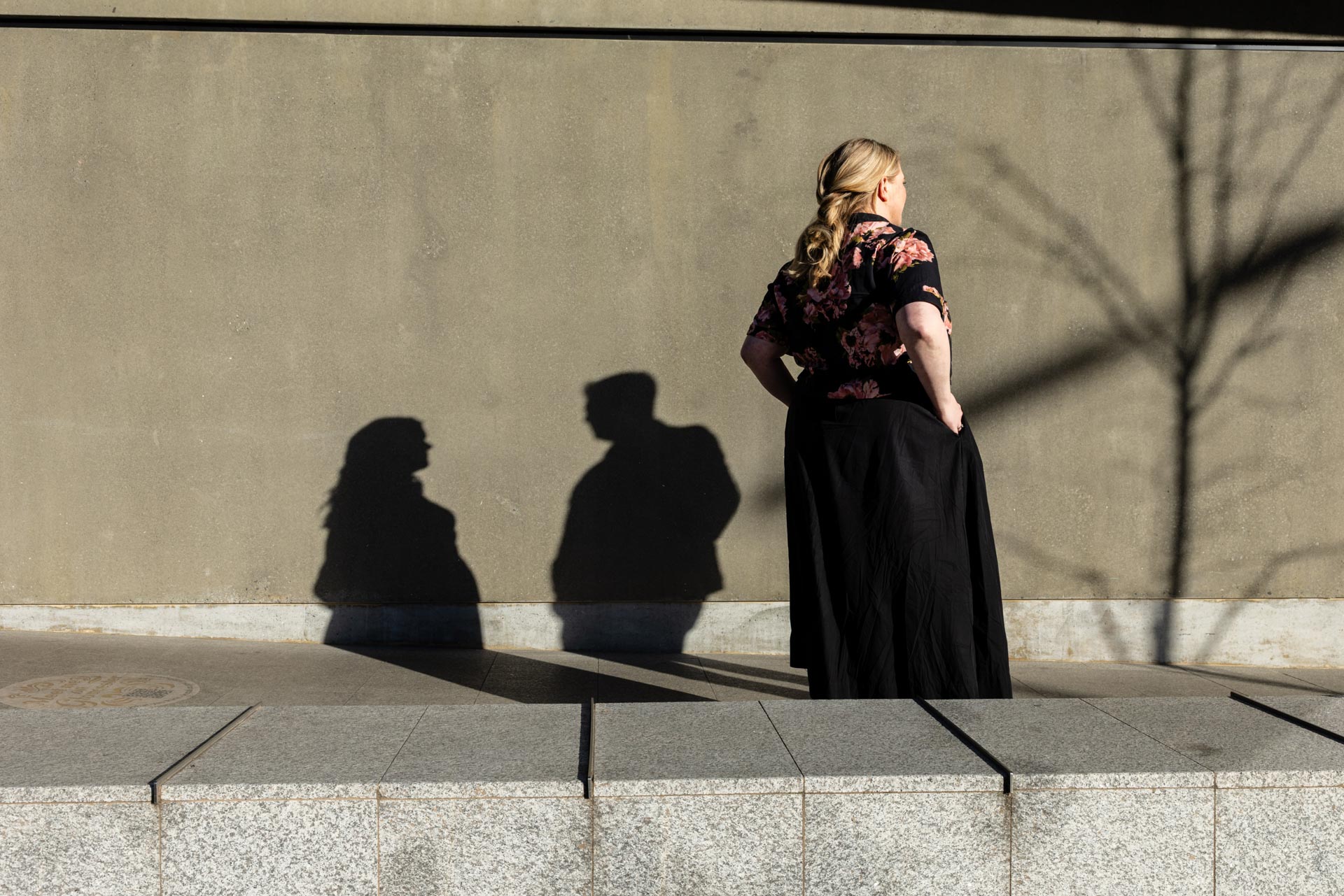 Long shadows of a woman and a man crossing a sunlit plaza