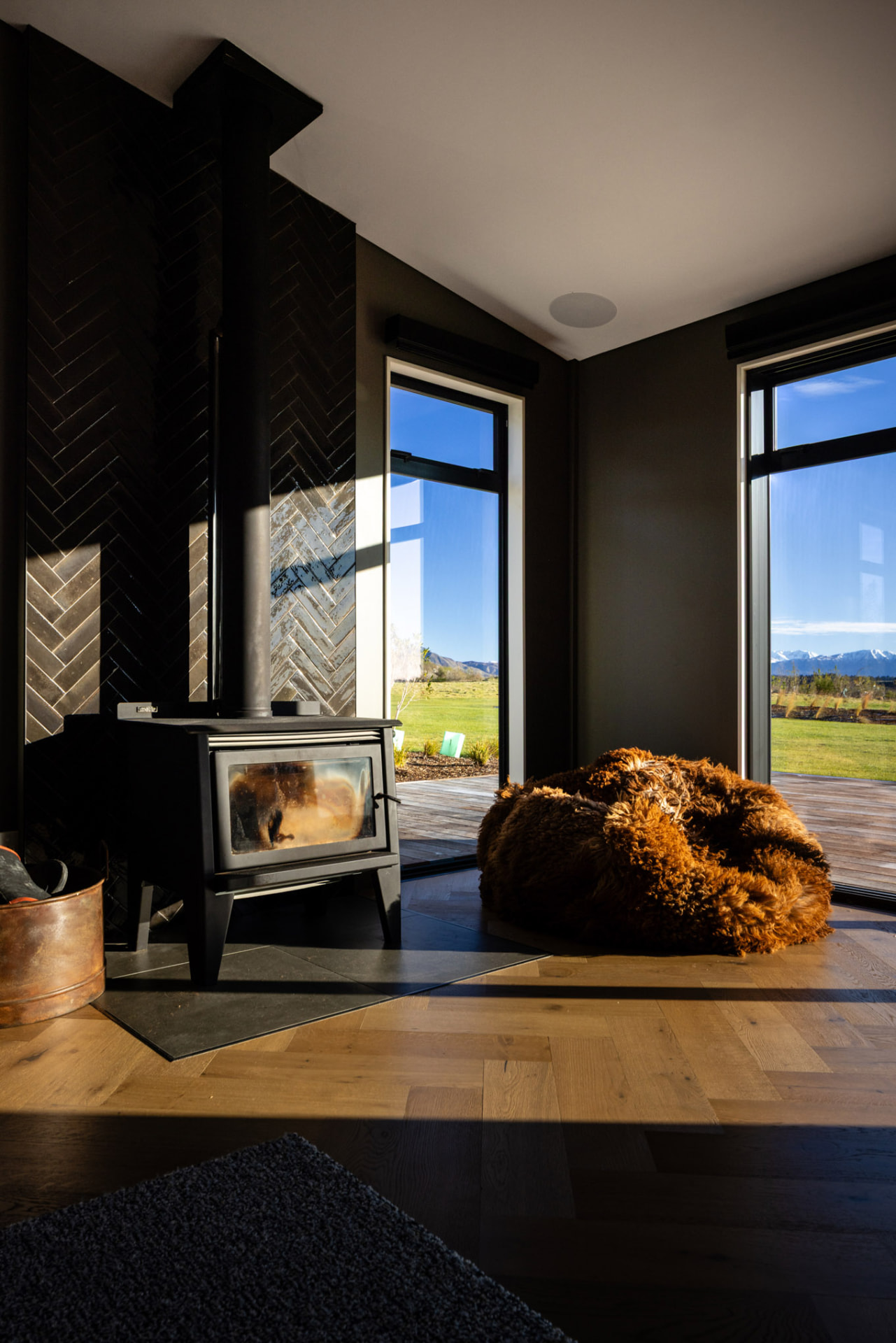 A sunny corner of Whakahā with beanbag, fireplace and full height windows with a view.