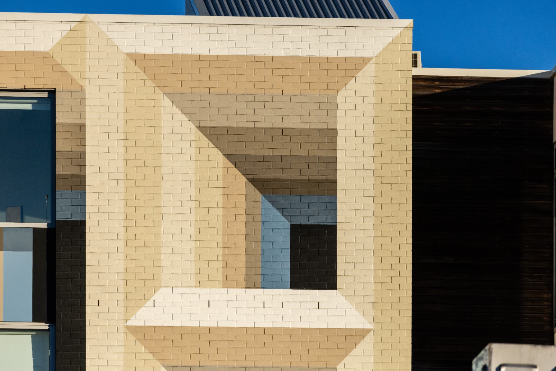 A painted brick wall with vertical stripes of tan, sky blue and dark brown