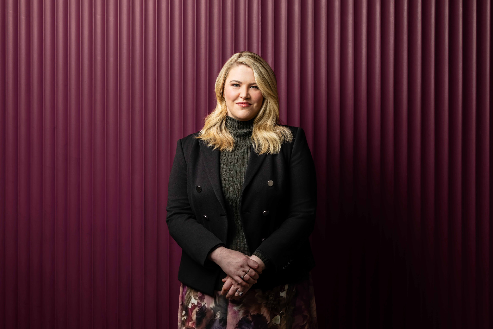 Camille standing against a deep red corrugated wall