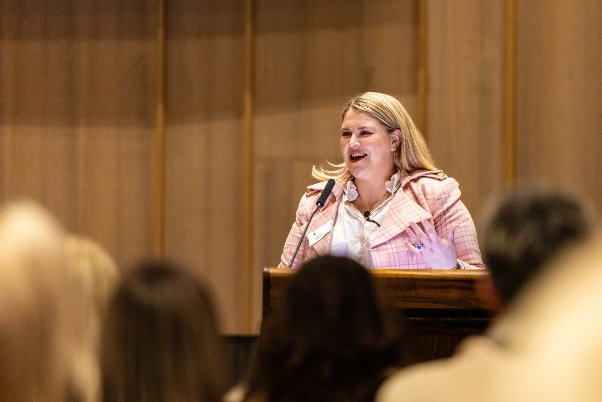 Camille Hughes speaking at a lectern, gesturing to the audience