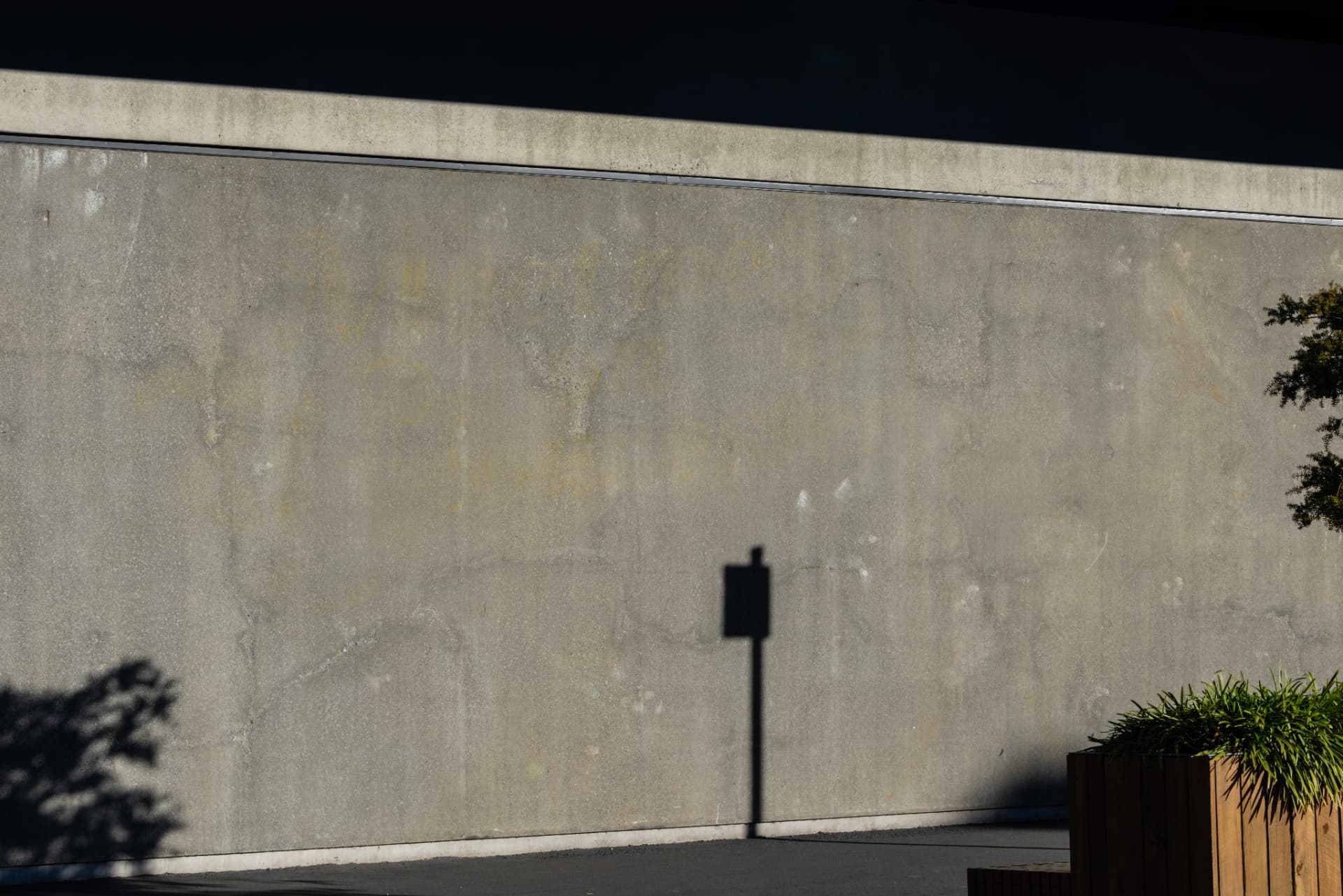 A concrete wall with the shadow of a signpost