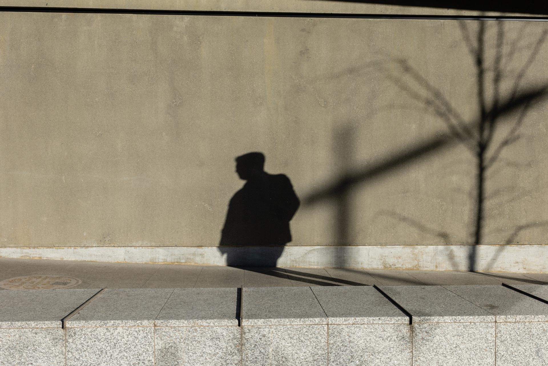 Long shadow of a man crossing a sunlit plaza