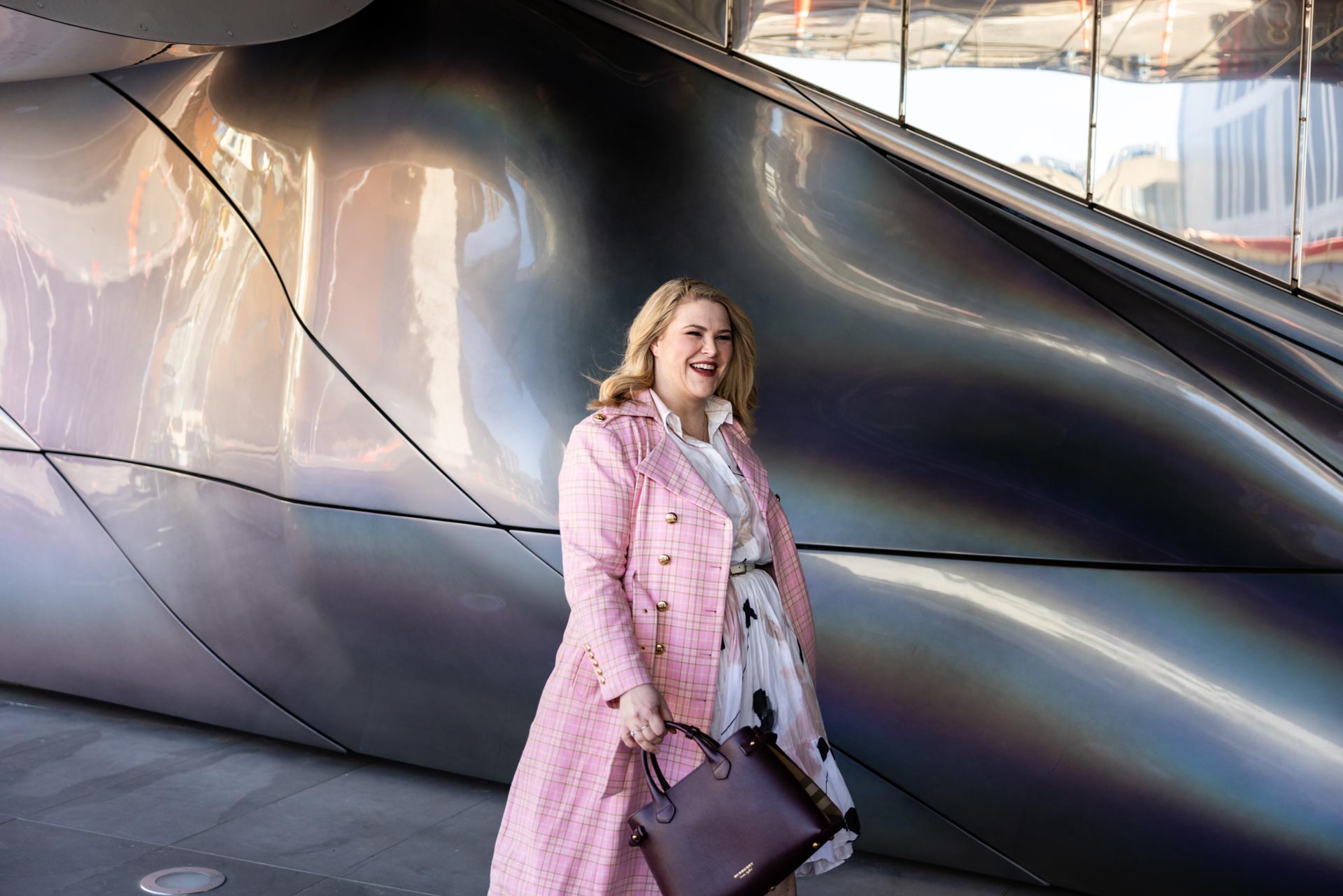 Camille Hughes walking past a reflective steel wall