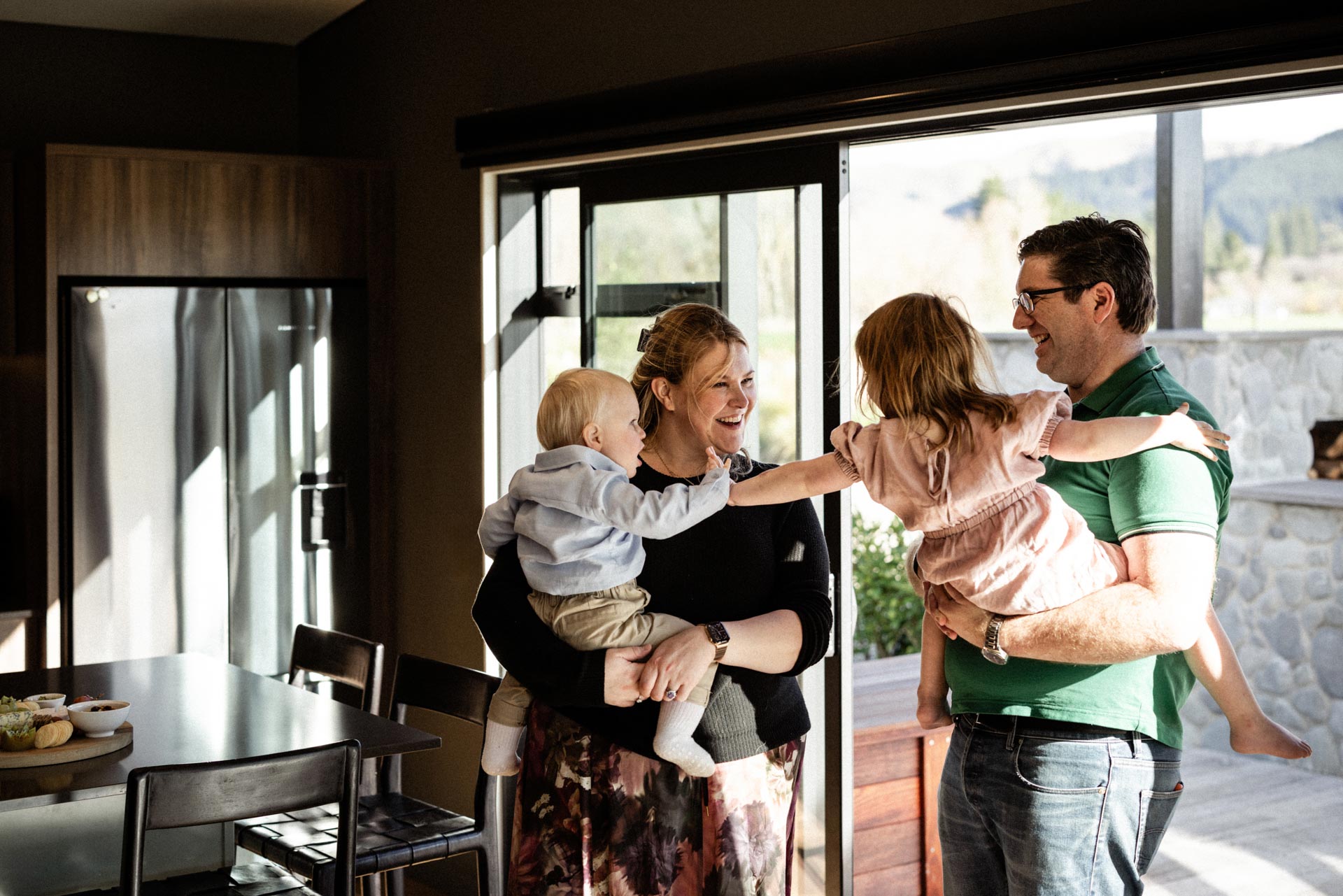Camille and Chris enter Whakahā holding their small children, who are high-fiving.