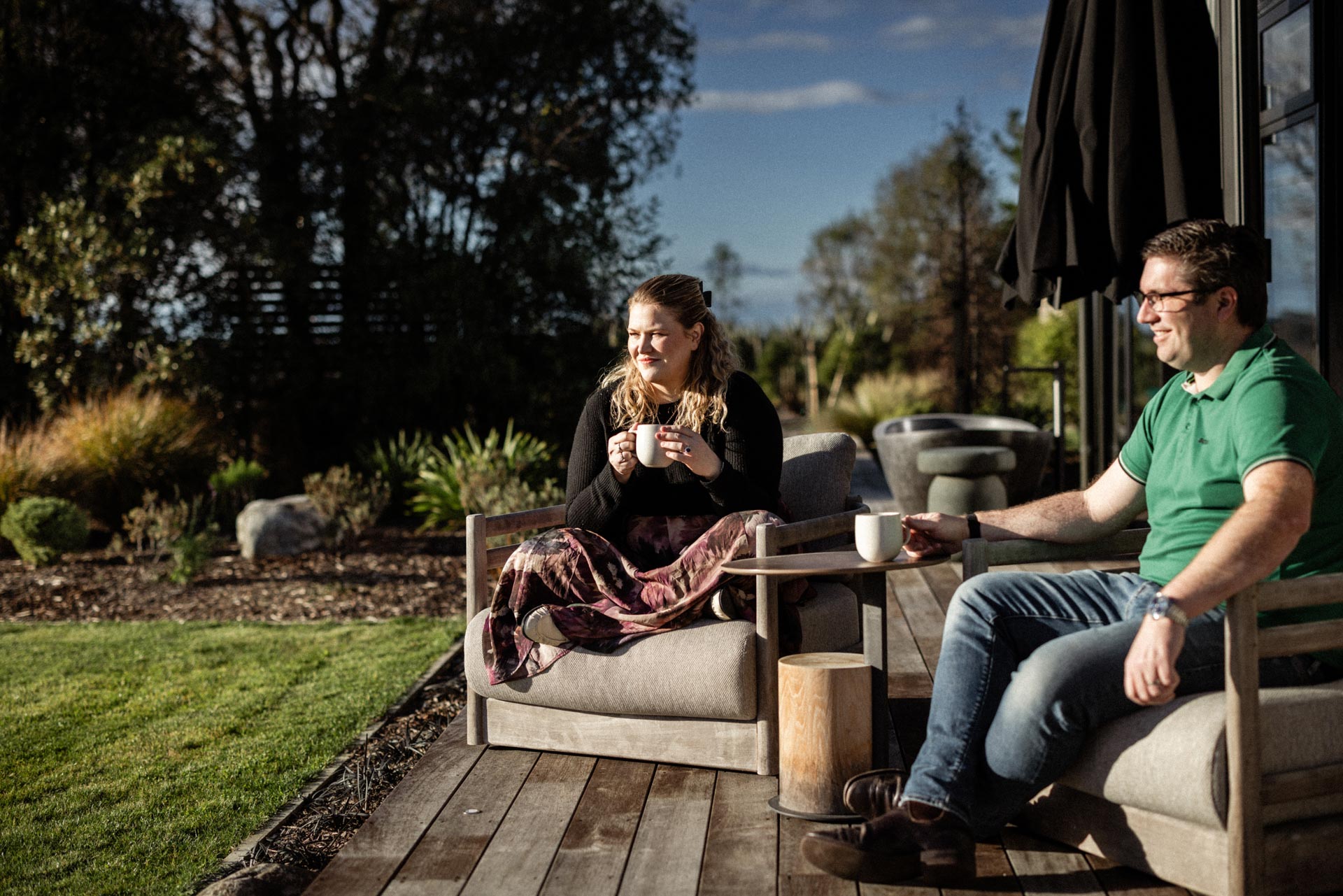 Camille and Chris sitting outside with morning coffee at Whakahā