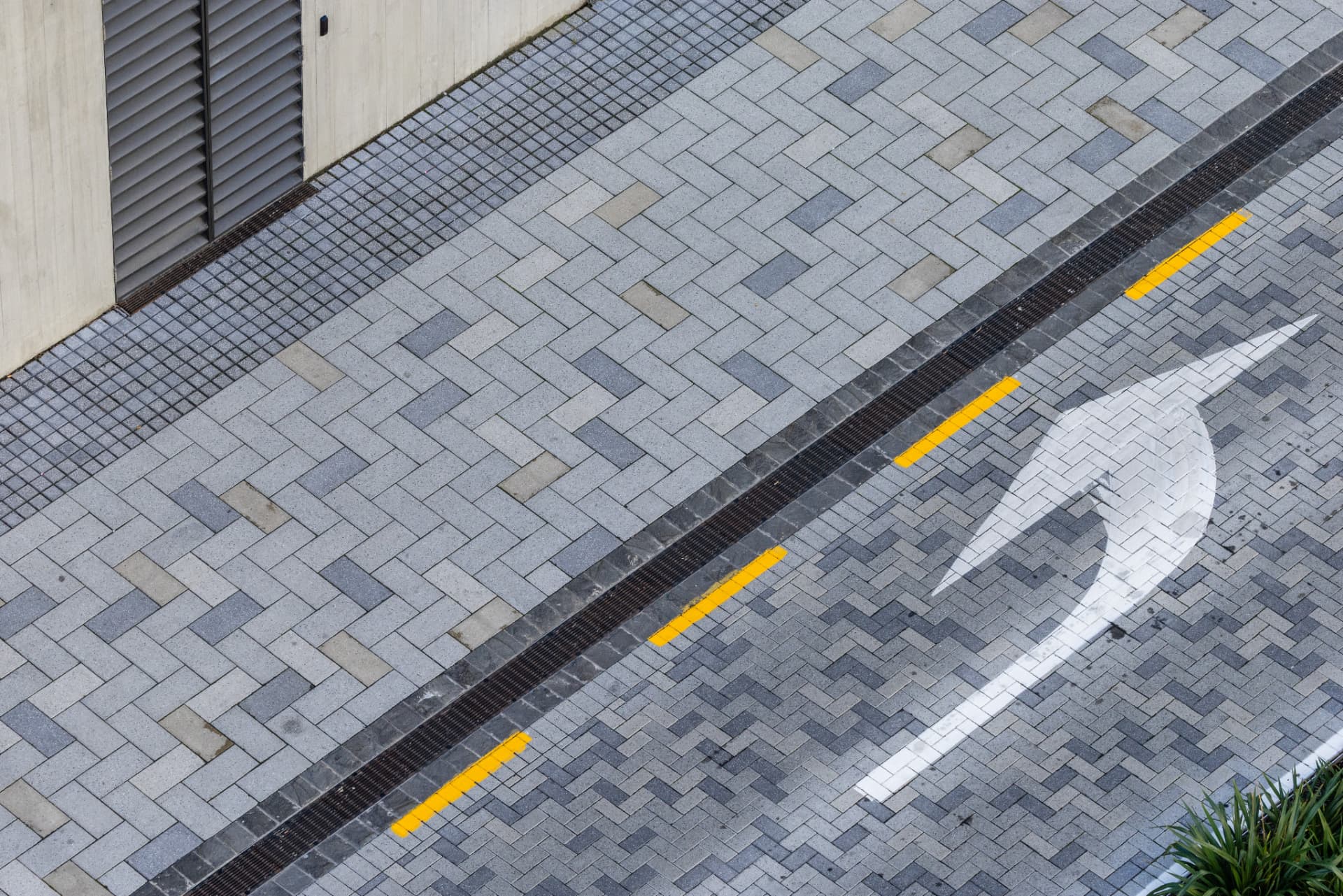 A large arrow painted on a brick lined street.